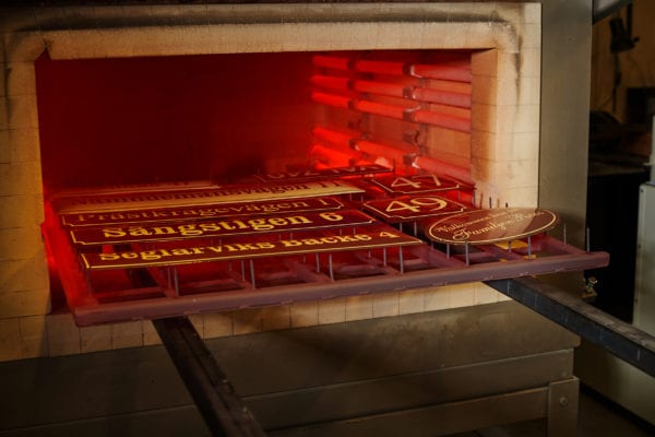 Skillinge Emalj emaljskylt - Den vita textemaljen har smält i 795 grader, detta är normalt skyltens tredje och sista bränning, varje färg bränns var för sig.